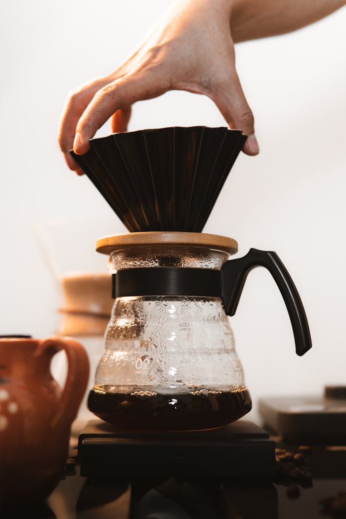 Close-up of hand placing filter in coffee brewing process with drip method.
