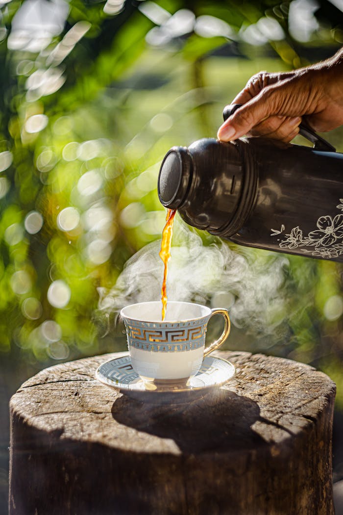 A close-up of steaming tea being poured into a teacup outdoors in Viçosa, Brazil.