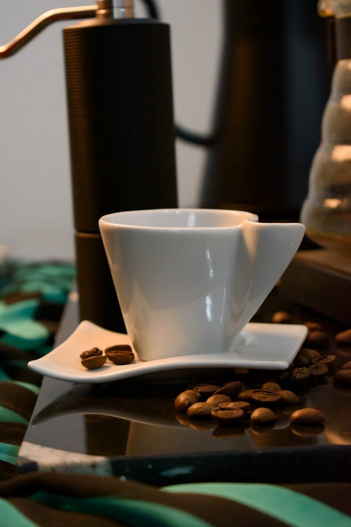 Stylish coffee cup with grinder and coffee beans on a modern table setting.